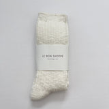 Packaged sock with 'Le Bon Shoppe' label on a gray background