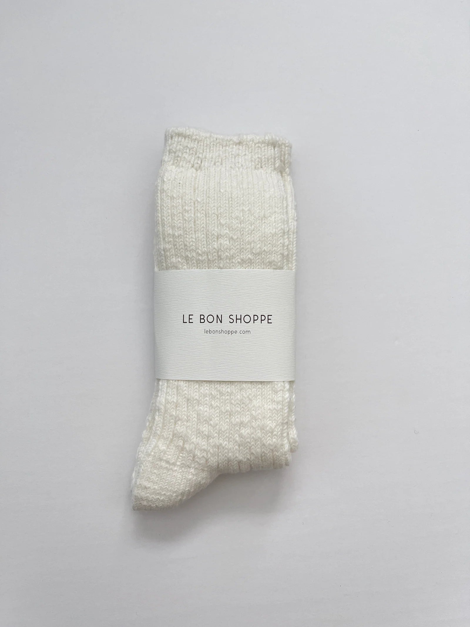 Packaged sock with 'Le Bon Shoppe' label on a gray background