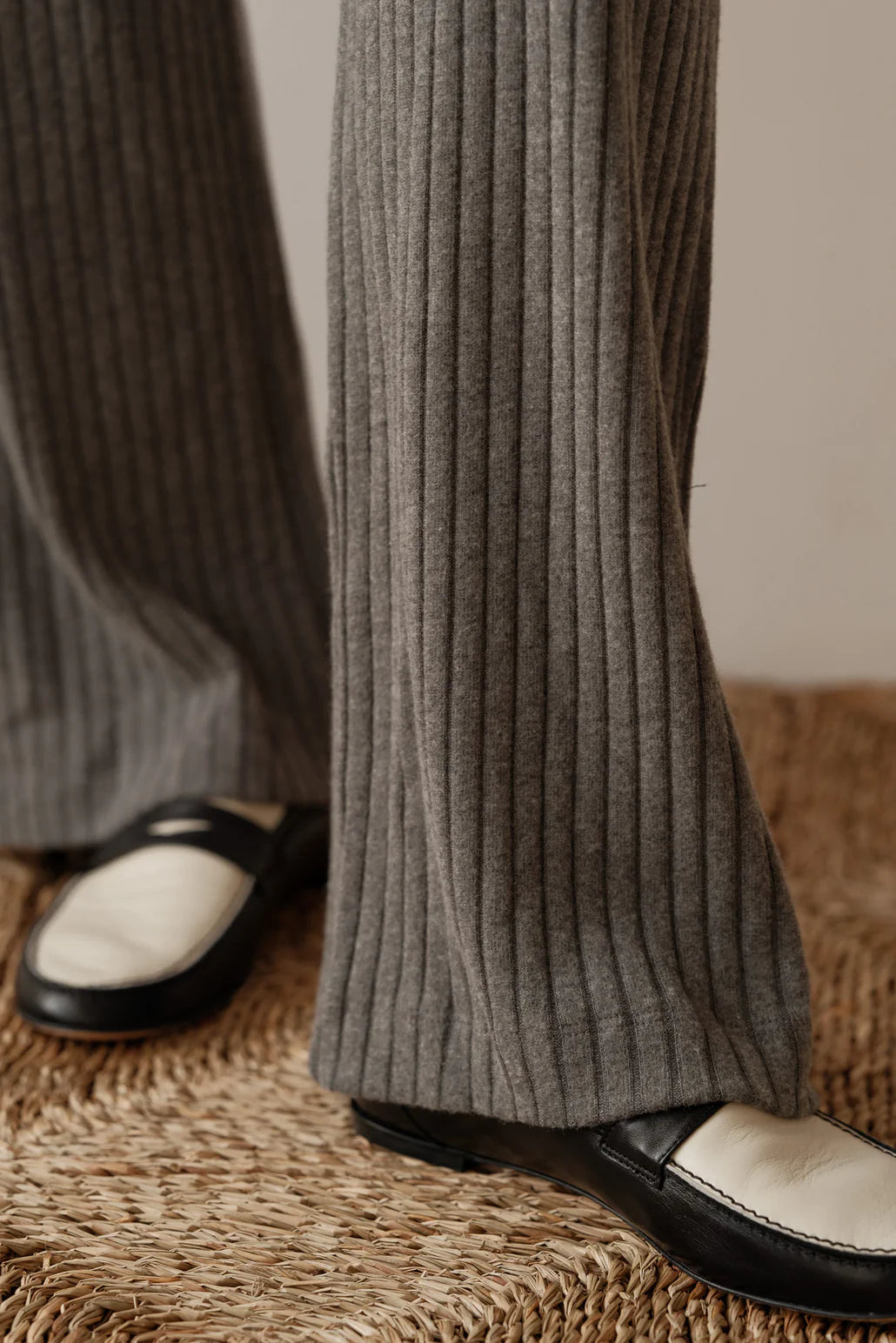 A close up detail image of the Sweater Rib Simple in Charcoal bottom hem, styled on a female model wearing a black and white loafer shoe