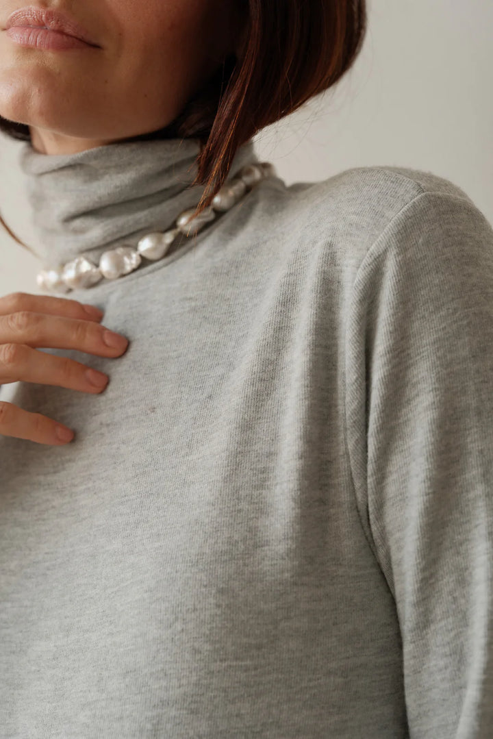 Close up detail image of the turtleneck and shoulder of the Sweater Turtleneck in Heather Grey on a female model