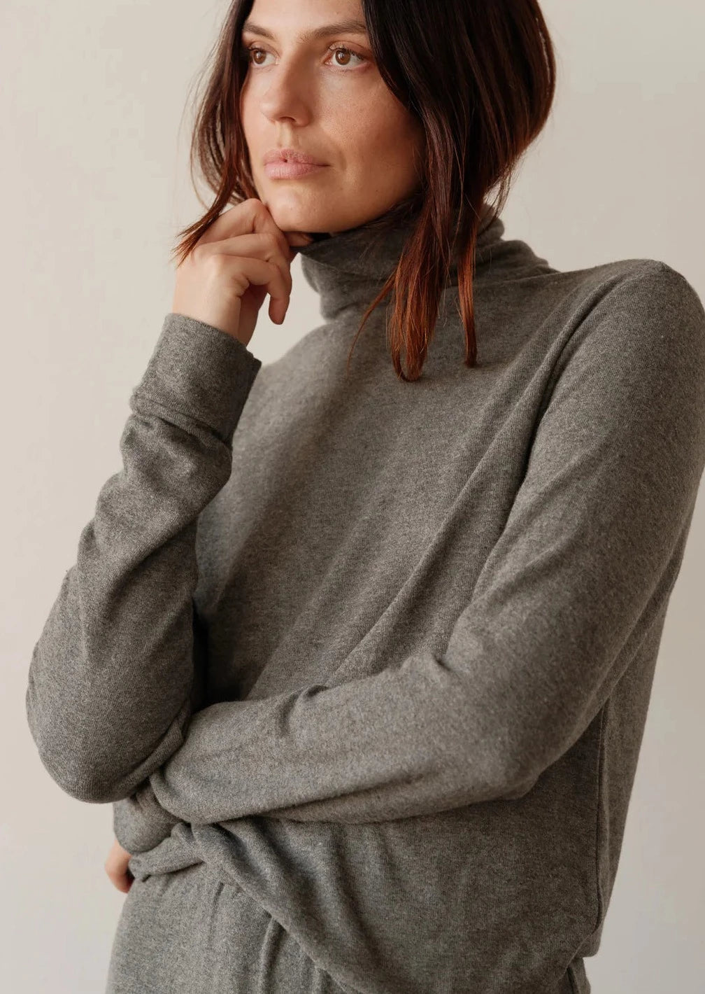 A close up shot of a female model posing while wearing the Sweater Turtleneck in Charcoal Grey