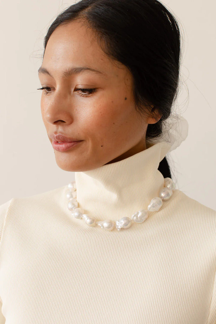 A close up detail image of the neckline of the Rib Turtleneck in Creme