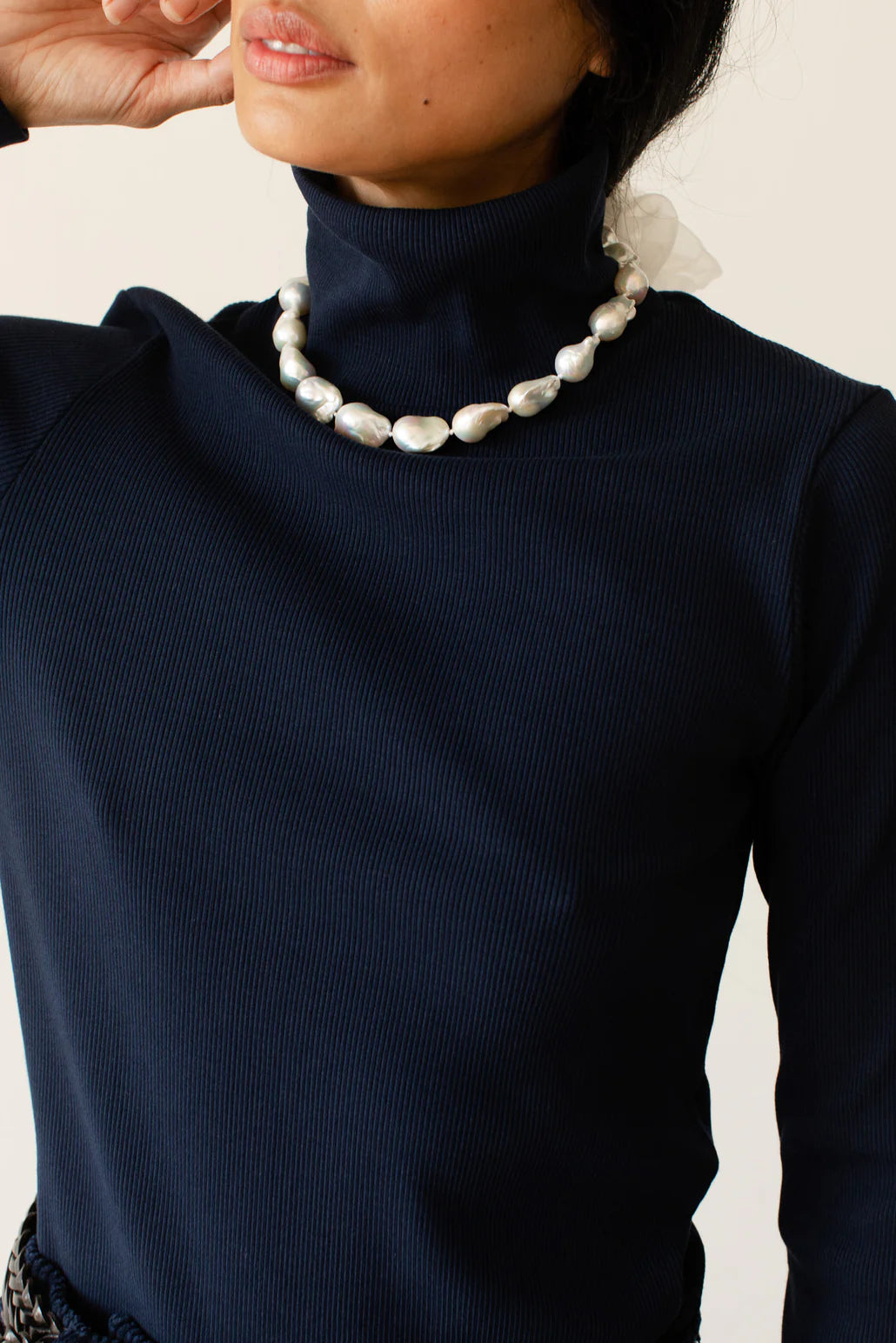 A close up detail image of the turtleneck and front of the Rib Turtleneck in navy on a female model