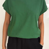 Person wearing a green t-shirt and black pants against a white background