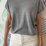 Person wearing a gray t-shirt and white pants against a colorful abstract background