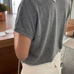 Person wearing a gray t-shirt with a brand tag in an indoor setting