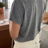 Person wearing a gray t-shirt with a brand tag in an indoor setting