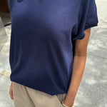 Person wearing a navy blue t-shirt and beige pants on a sidewalk.