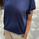 Person wearing a navy blue t-shirt and beige pants on a sidewalk.