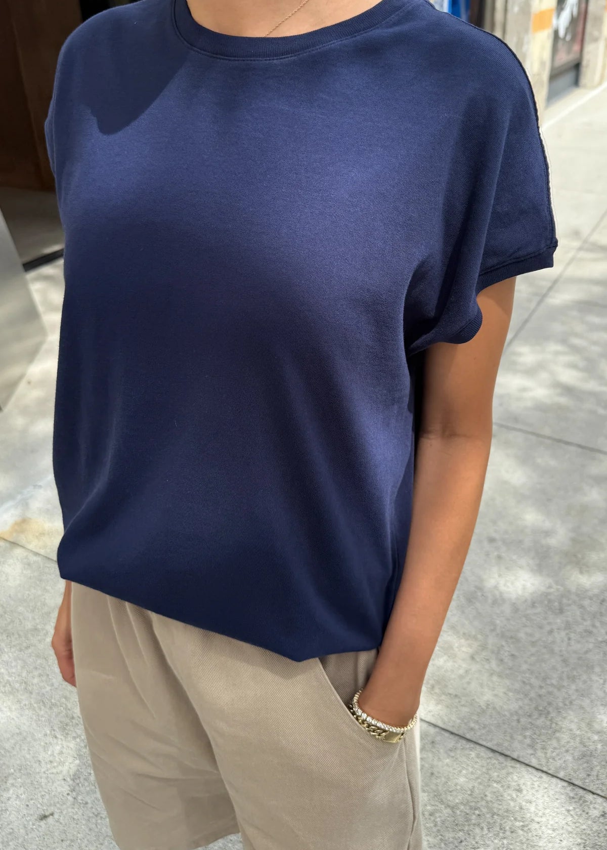 Person wearing a navy blue t-shirt and beige pants on a sidewalk.