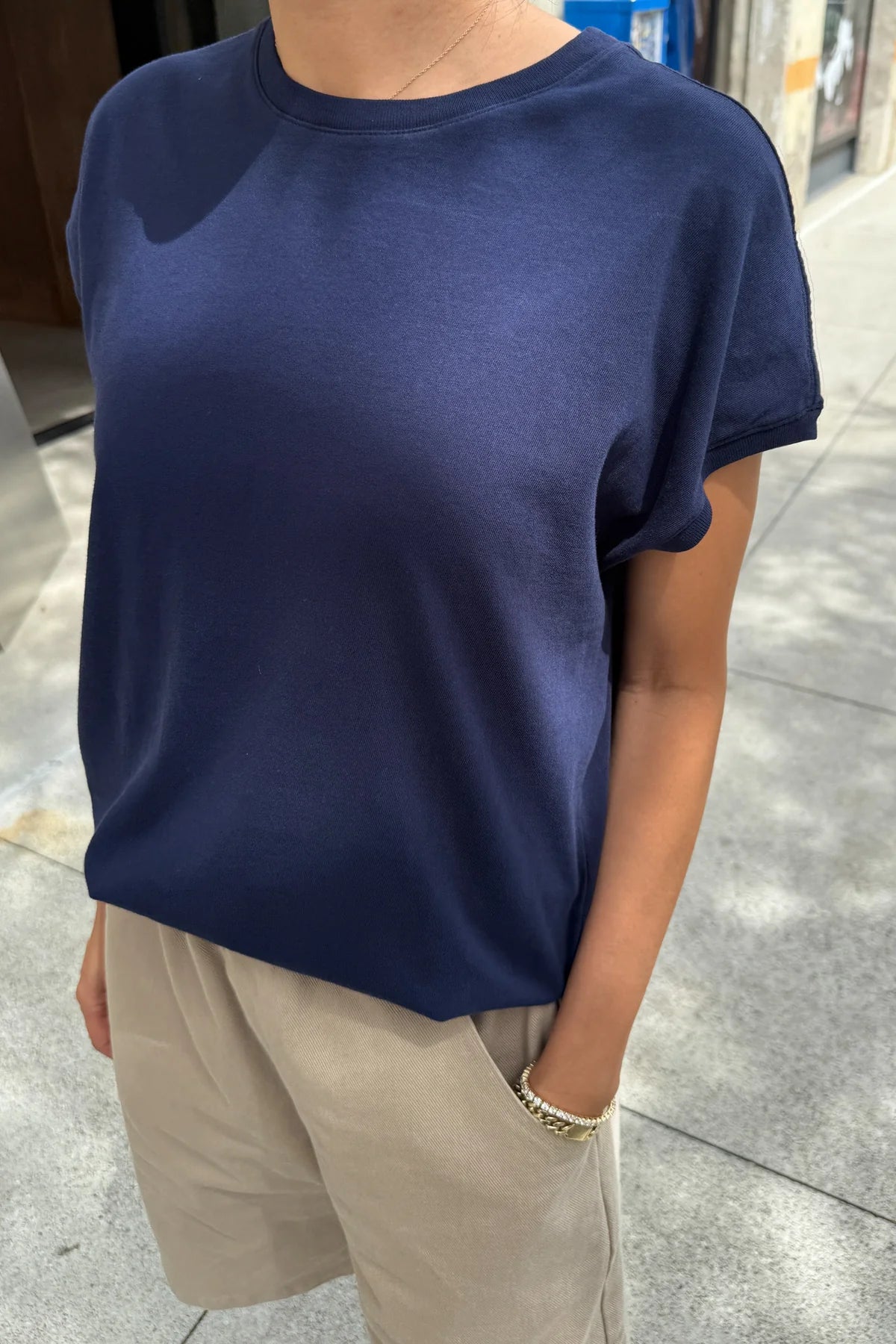 Person wearing a navy blue t-shirt and beige pants on a sidewalk.