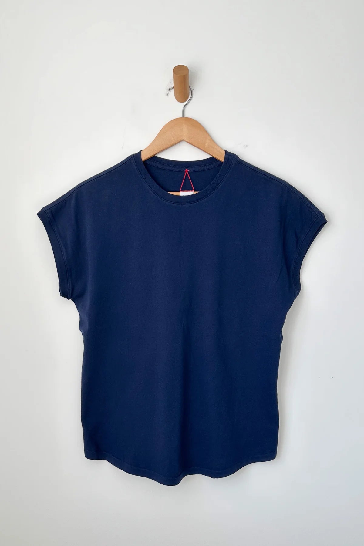 Navy blue t-shirt on a wooden hanger against a white background