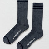 Pair of gray socks with black stripes and 'Le Bon Shoppe' branding on a light gray background