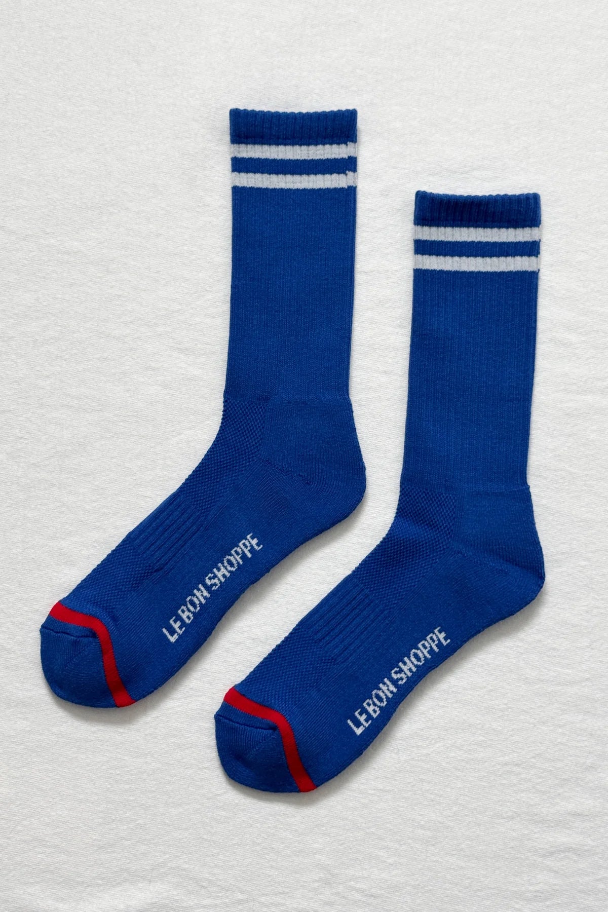 Cobalt socks with white stripes and Le Bon Shoppe branding on white background.
