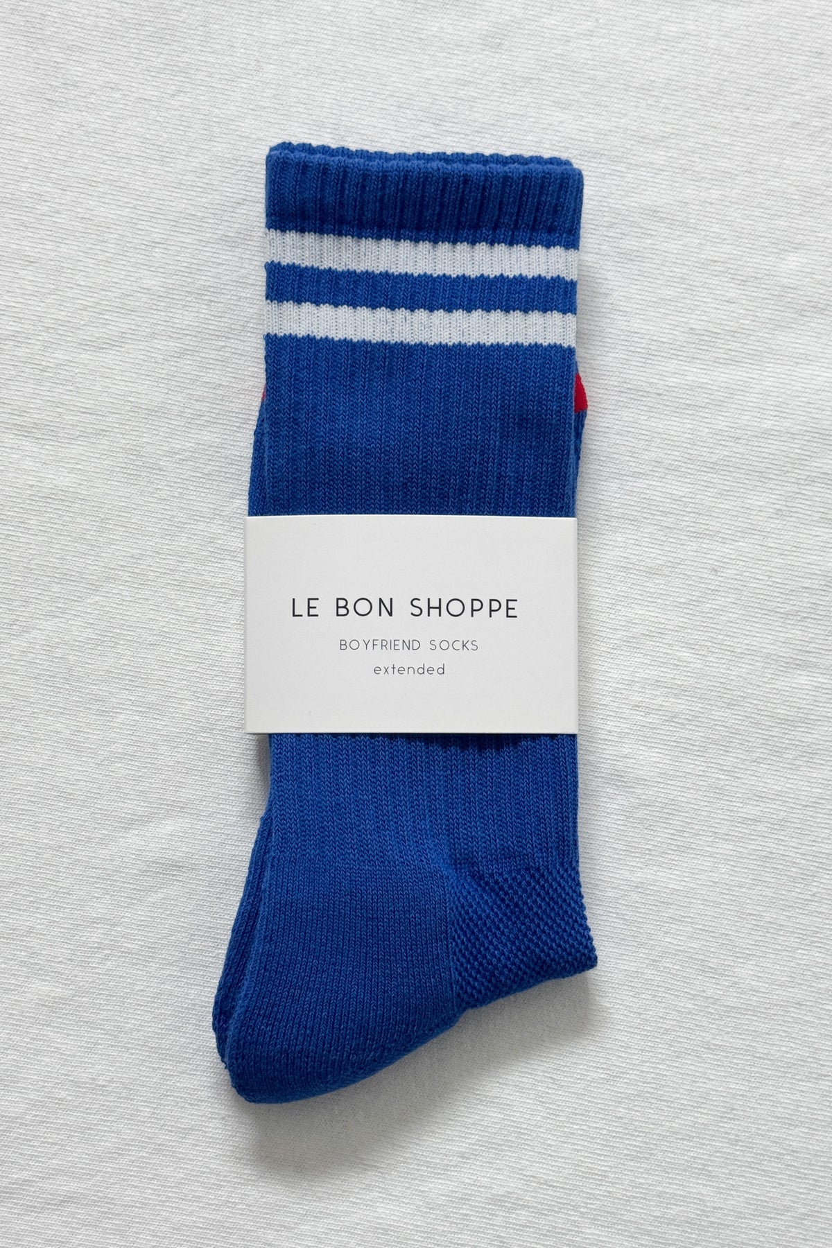 Cobalt socks with white stripes in Le Bon Shoppe packaging on white background.