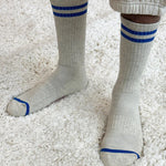 White socks with blue stripes worn on a light carpet