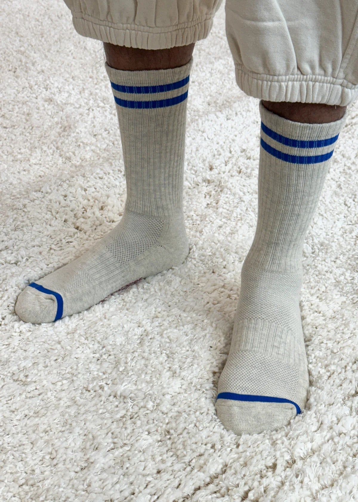 White socks with blue stripes worn on a light carpet