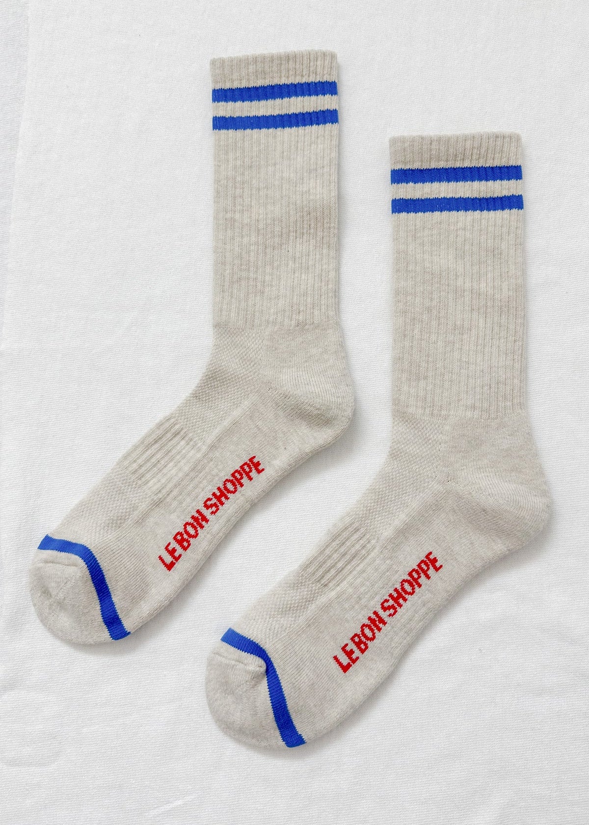 Pair of gray socks with blue stripes and red text on a white background
