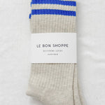 Folded socks with blue stripes and 'Le Bon Shoppe' label on a light gray background