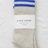 Folded socks with blue stripes and 'Le Bon Shoppe' label on a light gray background