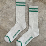 Pair of gray socks with green stripes and text on a concrete surface