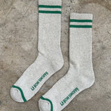 Pair of gray socks with green stripes and text on a concrete surface
