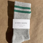Gray sock with green stripes on a brown background, featuring 'Le Bon Shoppe' label.