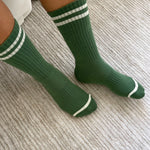 Person wearing green socks with white stripes on carpet floor