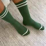 Person wearing green socks with white stripes on carpet floor