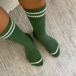 Person wearing green socks with white stripes on carpet floor