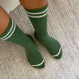 Person wearing green socks with white stripes on carpet floor