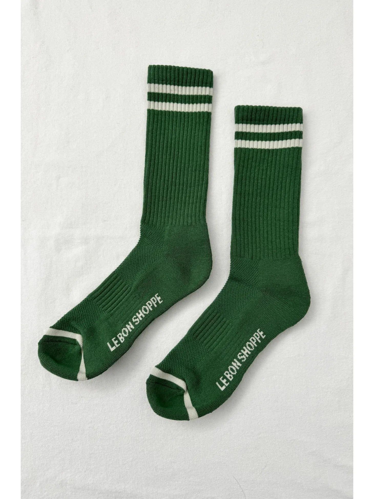 Green socks with white stripes and Le Bon Shoppe branding on white background