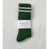 Green socks with white stripes in Le Bon Shoppe packaging on white background