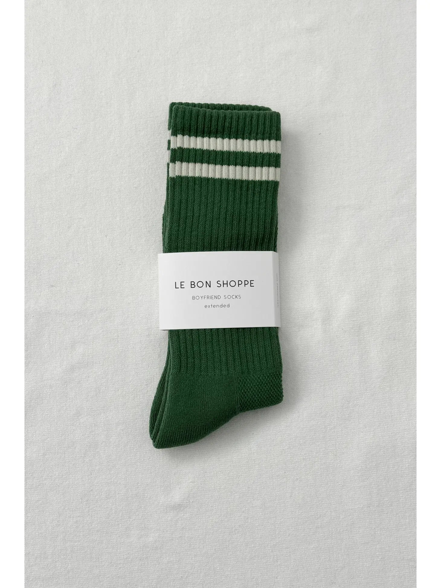 Green socks with white stripes in Le Bon Shoppe packaging on white background