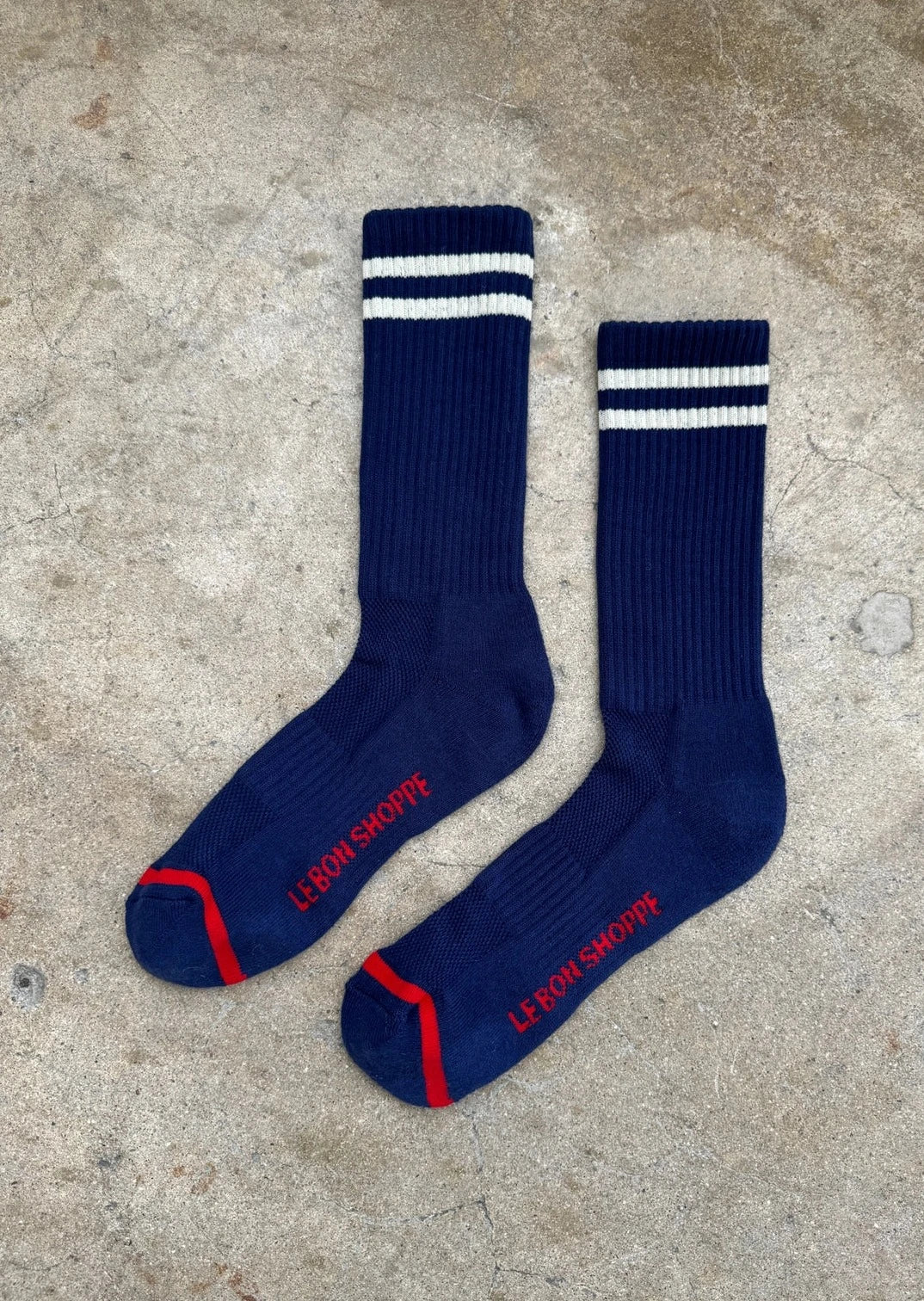 A pair of navy blue extended boyfriend socks with a white and red stripe on the ankle area.