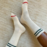 White socks with red and green stripes worn on a neutral background