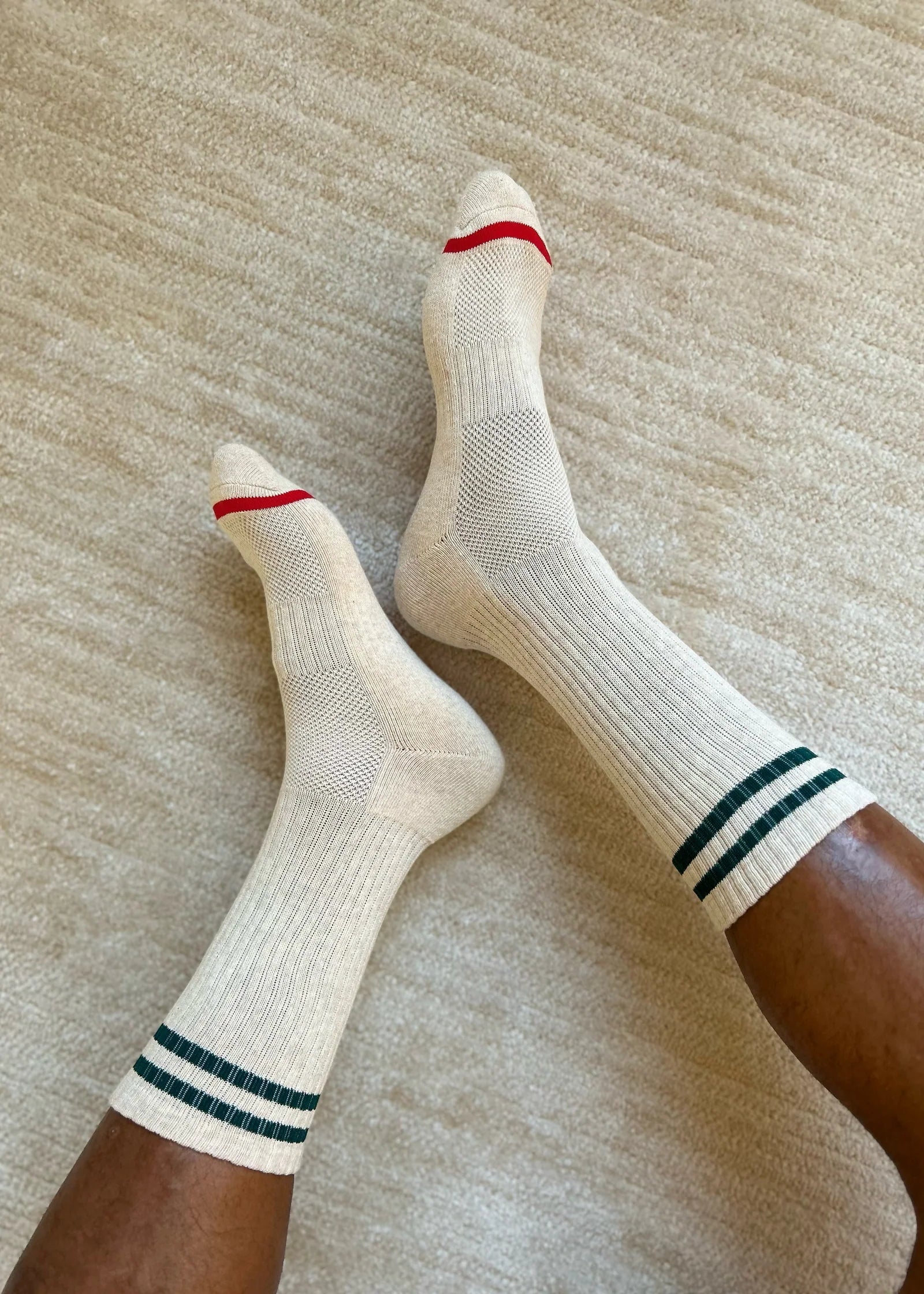 White socks with red and green stripes worn on a neutral background