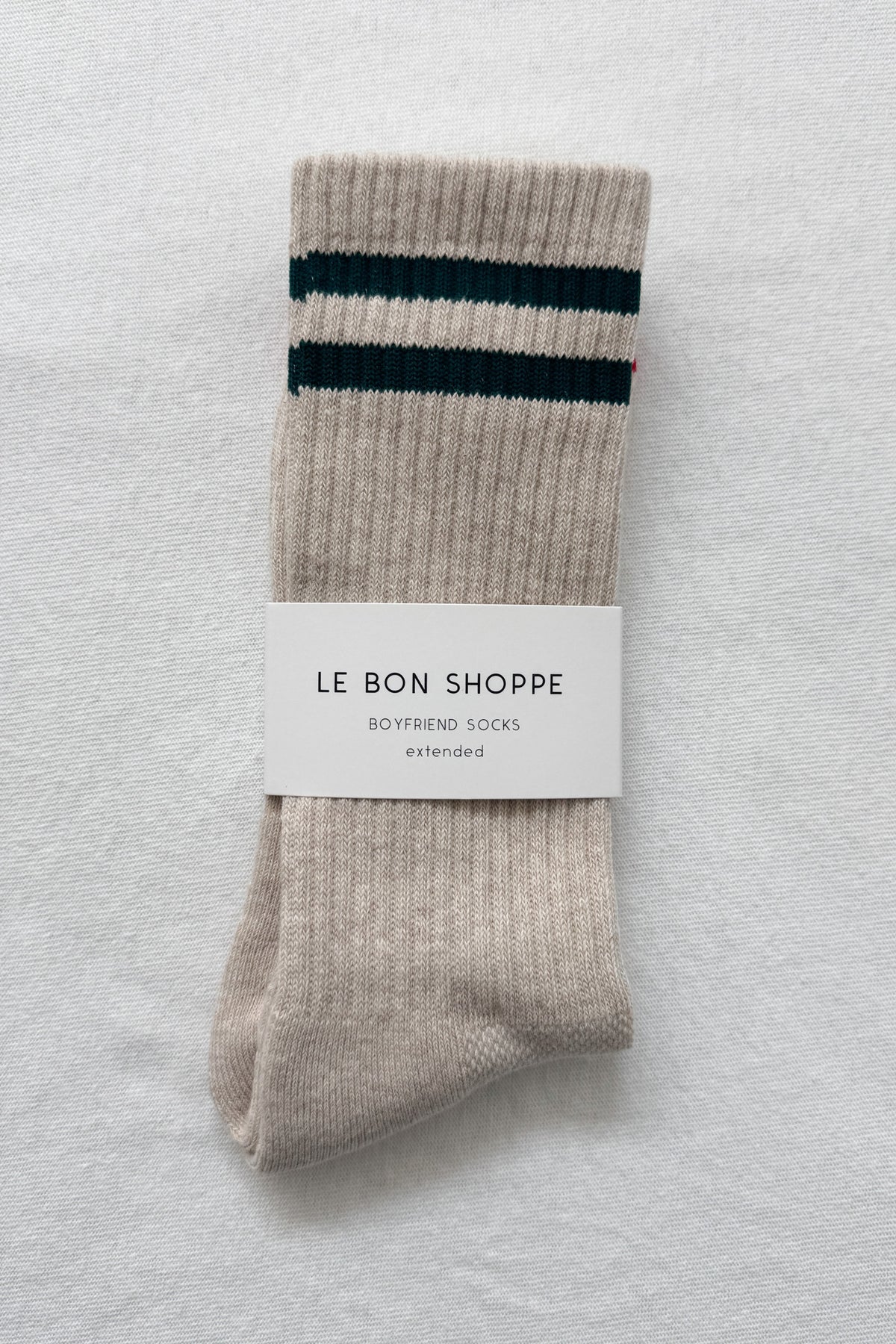 Pair of beige socks with green stripes on a light gray background, featuring a 'Le Bon Shoppe' label.
