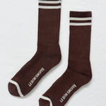 Pair of brown socks with white stripes and 'Le Bon Shoppe' branding on a light gray background