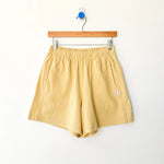 Yellow shorts on a wooden hanger against a white background