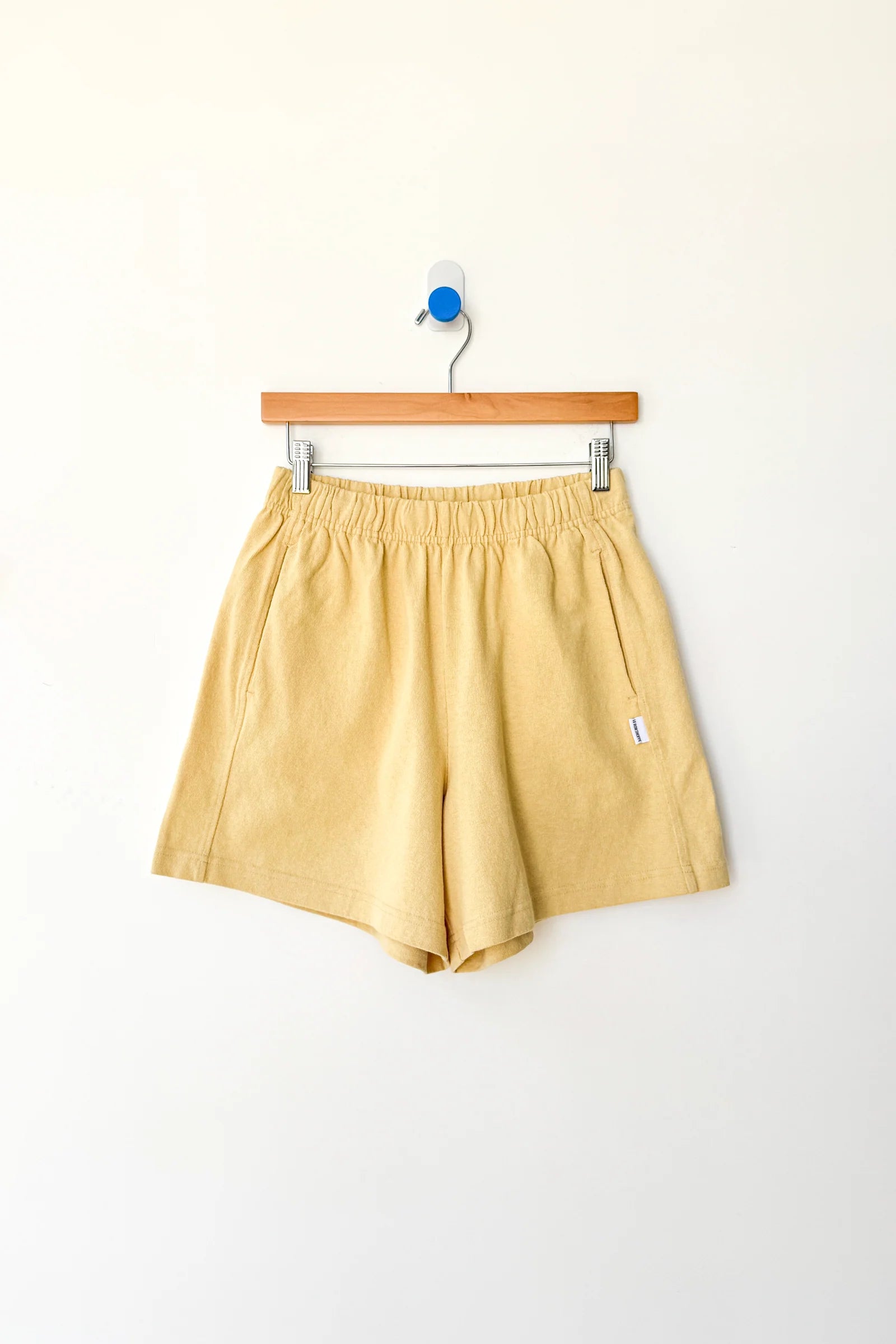 Yellow shorts on a wooden hanger against a white background