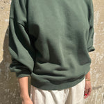 Person wearing a green sweater against a textured wall