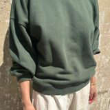 Person wearing a green sweater against a textured wall