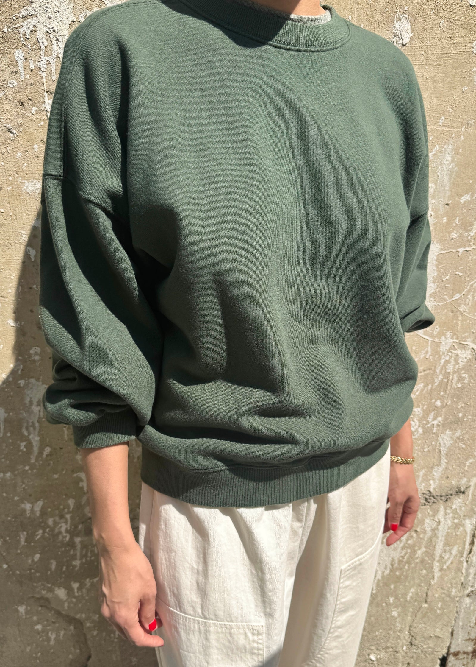 Person wearing a green sweater against a textured wall
