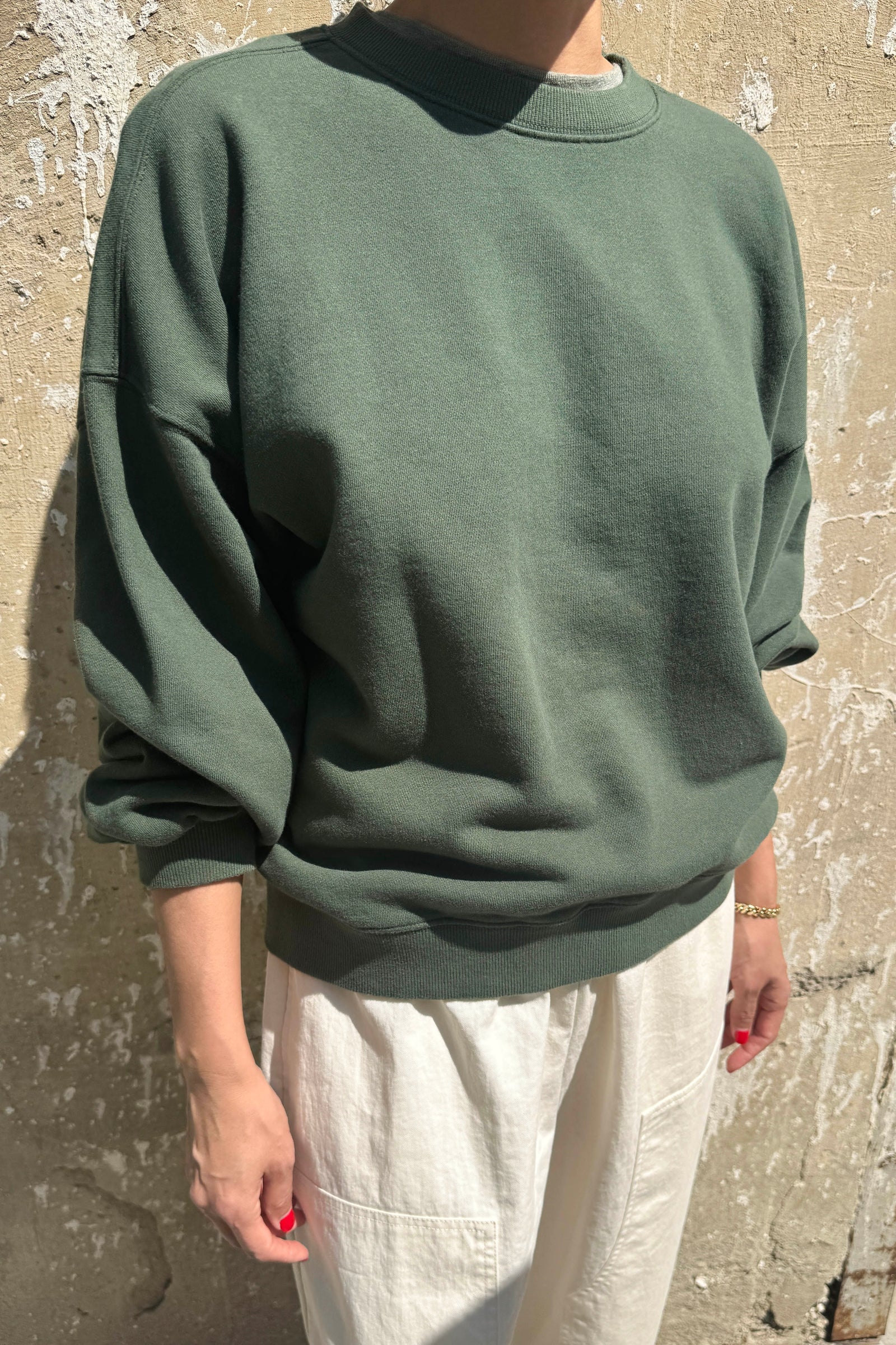 Person wearing a green sweater against a textured wall