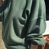 Person wearing a green sweatshirt with a blurred background
