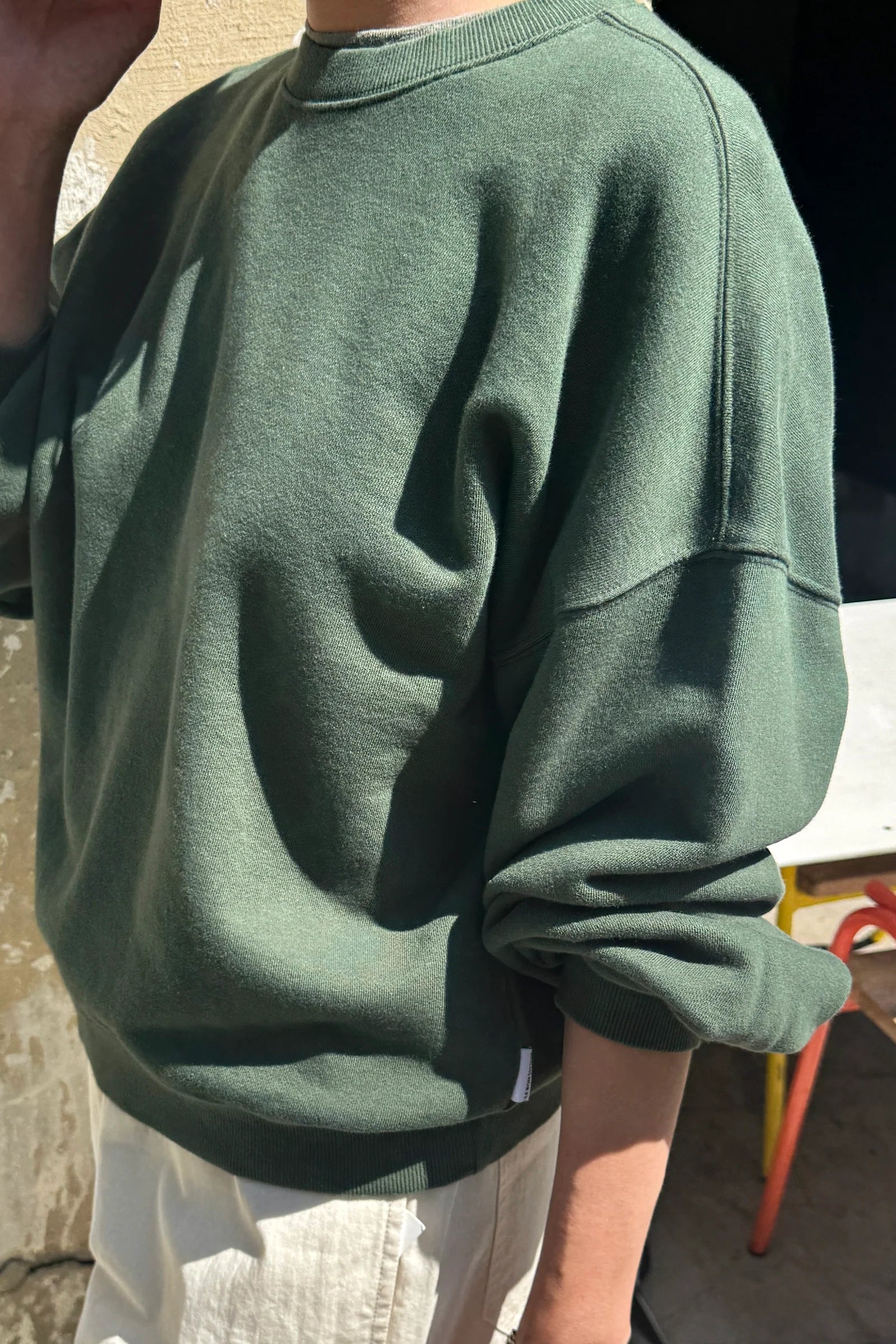 Person wearing a green sweatshirt with a blurred background