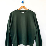 Green sweatshirt on a wooden hanger against a white background
