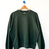 Green sweatshirt on a wooden hanger against a white background