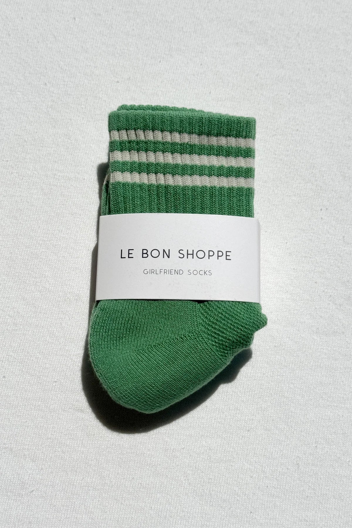 Green striped sock with 'Le Bon Shoppe' label on a light gray background